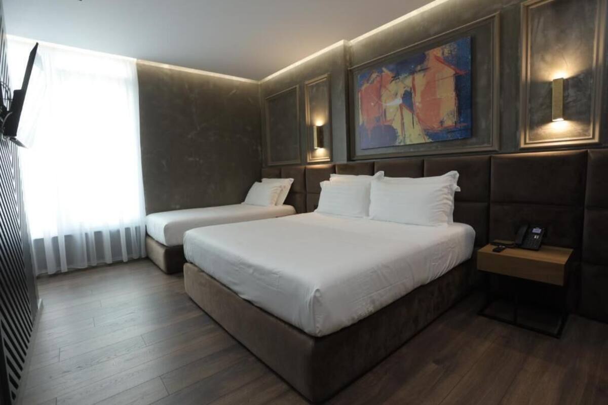 A hotel room with two beds, a large painting on the wall, and a bedside table with a phone.