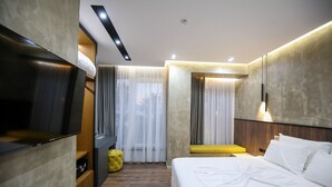 Une chambre d’hôtel moderne équipée d’un lit, d’une télévision, d’un bureau et d’un petit coin salon.