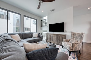 Relax in this stylish living room with a large sofa, armchair, and flat-screen TV.