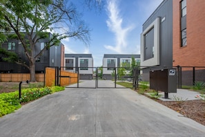 Stunning residential complex with a gated entrance, large windows, and beautifully manicured lawn.