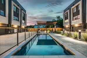 Relax by the rectangular pool surrounded by a tiled deck and shaded by a pergola.