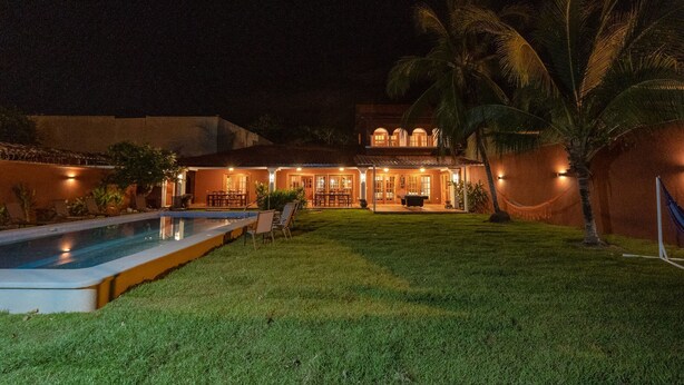 Una casa bien iluminada con piscina, mobiliario exterior y palmeras.