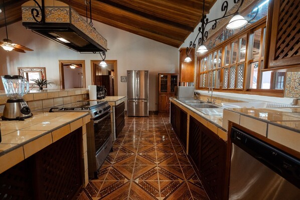 Uma cozinha com ilha central, eletrodomésticos de aço inoxidável e piso em ladrilho estampado.