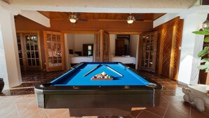 Una mesa de billar en una habitación con techo de madera y suelo de baldosas.
