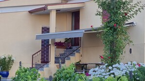 Un bâtiment doté d’un balcon, d’un escalier et d’un jardin où poussent des vignes.