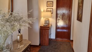 Un couloir avec une porte en bois, une lampe et un vase rempli de fleurs, posé sur un comptoir en marbre.