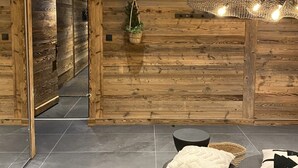 Moderni sisustus, jossa on puuseinät, musta sohva ja katosta roikkuva valaisin.