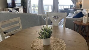 Et spiseområde med et rundt bord, stole, en potteplante og en ventilator i loftet.