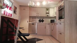 A modern kitchen with stainless steel appliances, light-colored cabinets, and a black countertop.