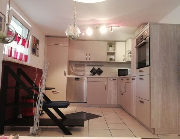 A modern kitchen with stainless steel appliances, light-colored cabinets, and a black countertop. - Comfortable and cozy vacation apartment in Höxter (H öxter)