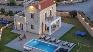 A stone building with a pool, outdoor seating, and a tennis table. - Dimokritos Villa V, Family Stay with Lawn & Play (Aggeliana, Rethymno)