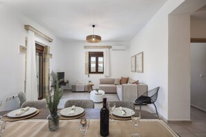 Een moderne woonkamer met een eethoek, een bank, een salontafel en een gedekte eettafel.