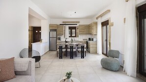 A modern kitchen with a central island, dining chairs, and a sofa. - Dimokritos Villa V, Family Stay with Lawn & Play (Aggeliana, Rethymno)