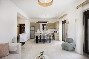 A modern kitchen with a central island, dining chairs, and a sofa.