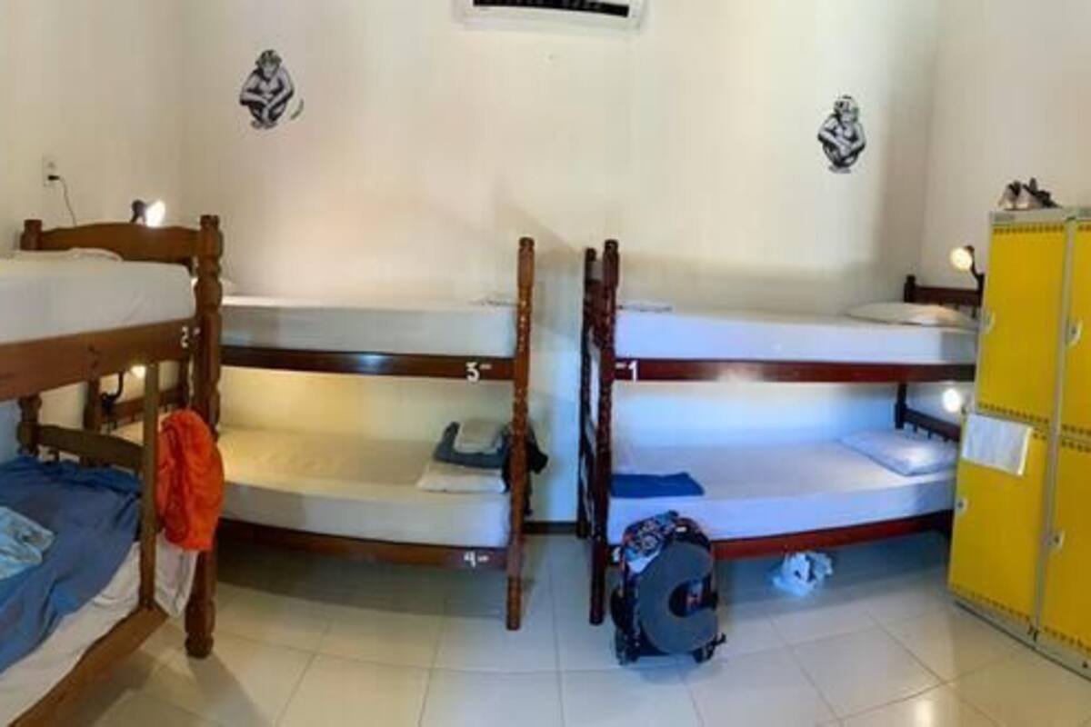 A dormitory room with bunk beds, a wardrobe, and a mirror.