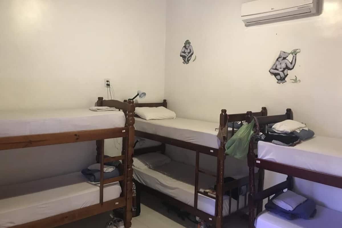 A dormitory room with bunk beds, an air conditioning unit, and wall decorations.