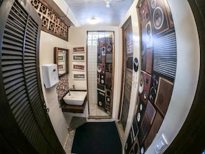 A compact bathroom with a sink, mirror, and decorative wall panels. - Biergarten Hostel (Angra dos Reis)