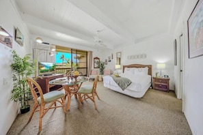 Una habitación con cama, una mesa de comedor con sillas, televisión y balcón con vistas.