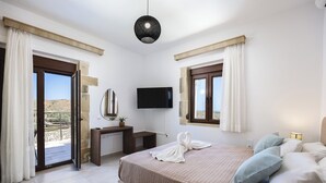 Una camera da letto con un letto, una scrivania, una TV e un balcone.