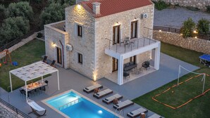 Una casa in pietra con piscina, area relax esterna e campo da tennis.