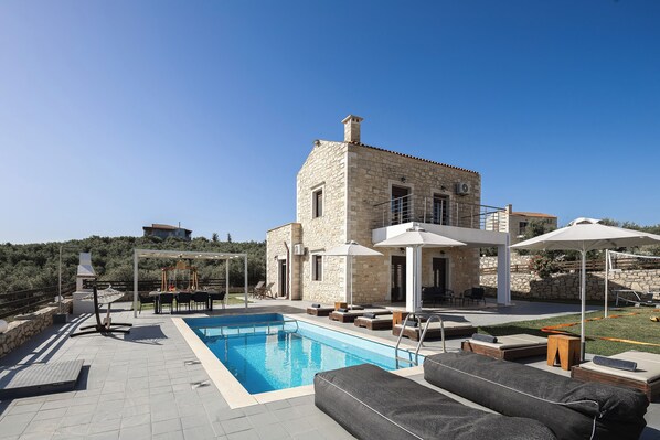 A stone building with a swimming pool, outdoor seating, and a view of the surrounding landscape.