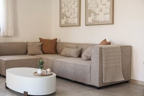 A modern living room with a sectional sofa, a round coffee table, and abstract wall art.