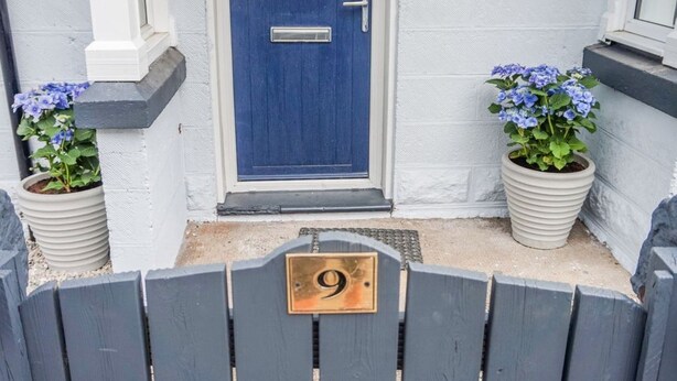 A blue door with a number 9 plaque, flanked by potted plants with blue flowers. - Seacot Cottage in the heart of the Highlands (Clachnaharry)