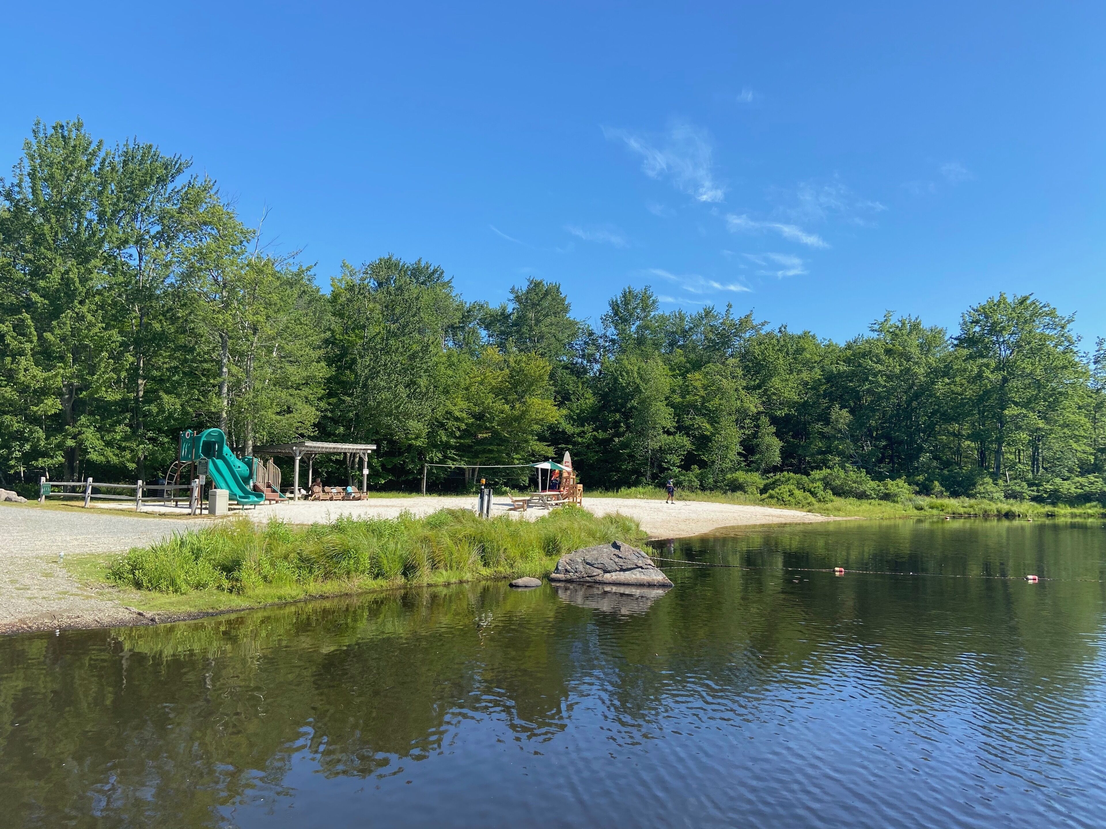 Een park aan het meer met een speeltuin, picknickplaats en een overdekt zitgedeelte.