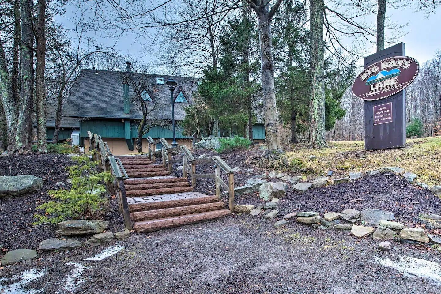 En trätrappa leder upp till en byggnad med en skylt som visar att det är Big Bass Lake Community Associations lokaler.