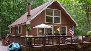 A cabin with a deck, outdoor seating, kayaks, and an American flag. - Classic Cabin in Pocono Mountain Resort (Gouldsboro)