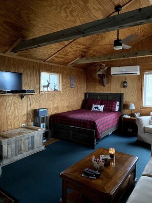 Un'accogliente camera in stile baita con un letto, una televisione, una panca di legno e una ventola a soffitto.
