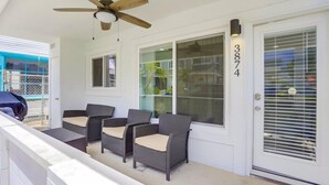 A covered porch with wicker furniture and a ceiling fan.