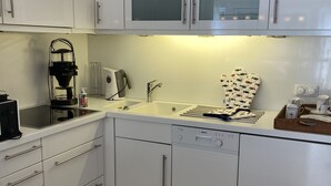 A modern kitchen with white cabinets, a Bosch dishwasher, a coffee maker, and a kettle. - Villa Senator-Marstall - stylish and close to the beach (Travemünde)