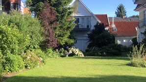 A residential area with a well-maintained lawn, a large tree, and houses with red-tiled roofs. - Villa Senator-Marstall - stylish and close to the beach (Travemünde)