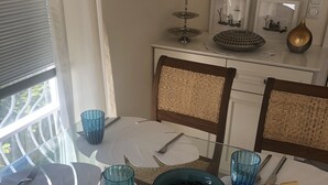 A dining area with a table set for two, featuring a blue glass bowl and plates, a knife, and a fork. - Villa Senator-Marstall - stylish and close to the beach (Travemünde)