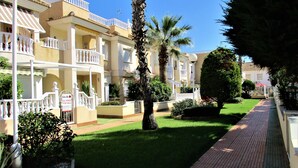 Un edificio residenziale con balconi, un vialetto lastricato e giardini curati.