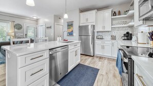 A modern kitchen with white cabinetry, stainless steel appliances, and pendant lighting. - Minutes to the Beach, Douglas, & Saugatuck! (Douglas)