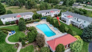 A two-story motel with a swimming pool, outdoor seating, and a red-roofed building. - Minutes to the Beach, Douglas, & Saugatuck! (Douglas)