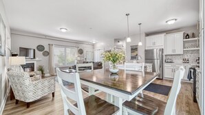 A modern kitchen with white cabinetry, a central island, and pendant lighting. - Minutes to the Beach, Douglas, & Saugatuck! (Douglas)