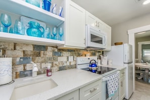 A kitchen with white cabinets, a microwave, a kettle, and a sink. - SOL Cottage, Best Experience in IRB, new AC, totally remodeled, free parking (Indian Rocks Beach)