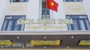 Exterior do Hotel & Restaurante Golden Inn, com uma bandeira proeminente e elementos arquitetônicos decorativos.