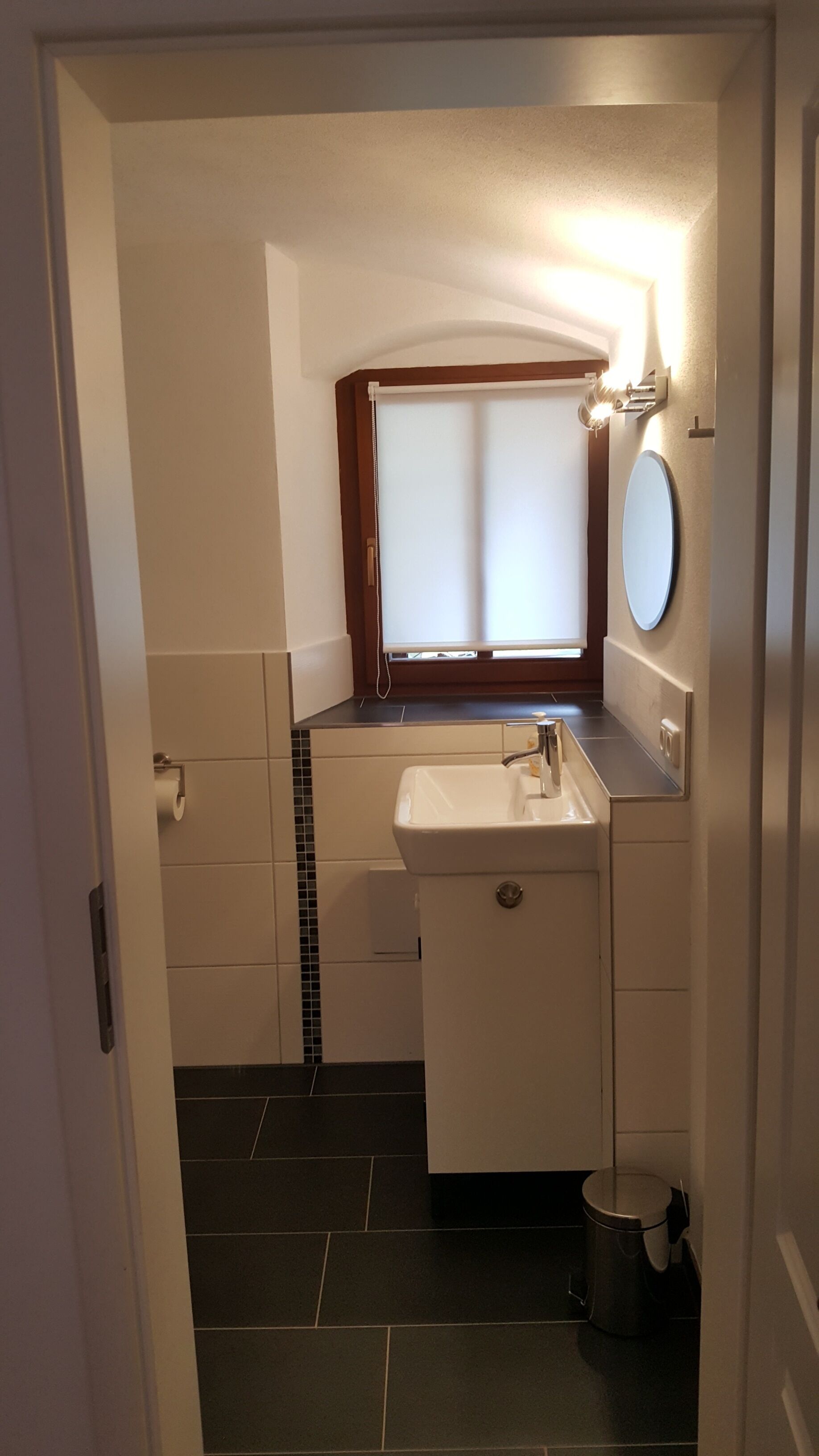 A bathroom with a white sink, a mirror, and a window with blinds.