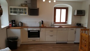 A compact kitchen with white cabinets, a built-in oven, a coffee maker, and a microwave. - Vacation apartment in a farmhouse in beautiful Maxen in Müglitztal, near Dresden. (Müglitztal)