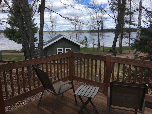 A wooden deck with two chairs and a small shed by a lake. - Cozy Cabin Getaway - Studio on ATV & Snowmobile Trail with Hi Speed WiFi (Conover)