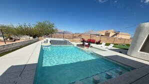 A swimming pool with clear water, a lounge area with red chairs, and a view of mountains in the background. - Bullhead oasis! Enjoy putt putt, view, pool & heated spa! (Bullhead City)