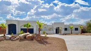 A modern building with multiple garage doors, palm trees, and a clear sky. - Bullhead oasis! Enjoy putt putt, view, pool & heated spa! (Bullhead City)