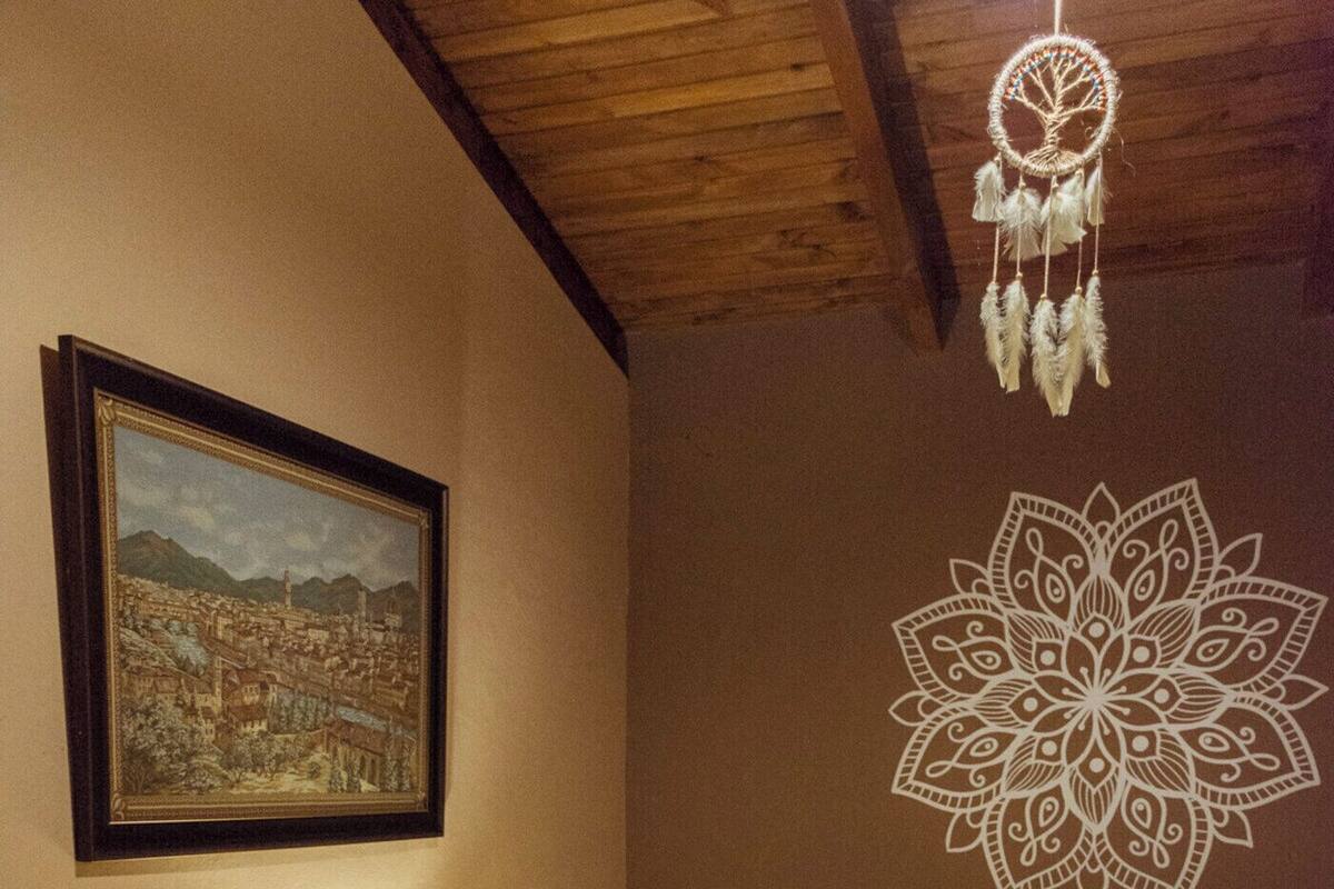 A room with two beds, a nightstand with a lamp, a framed picture on the wall, and a wall decoration.