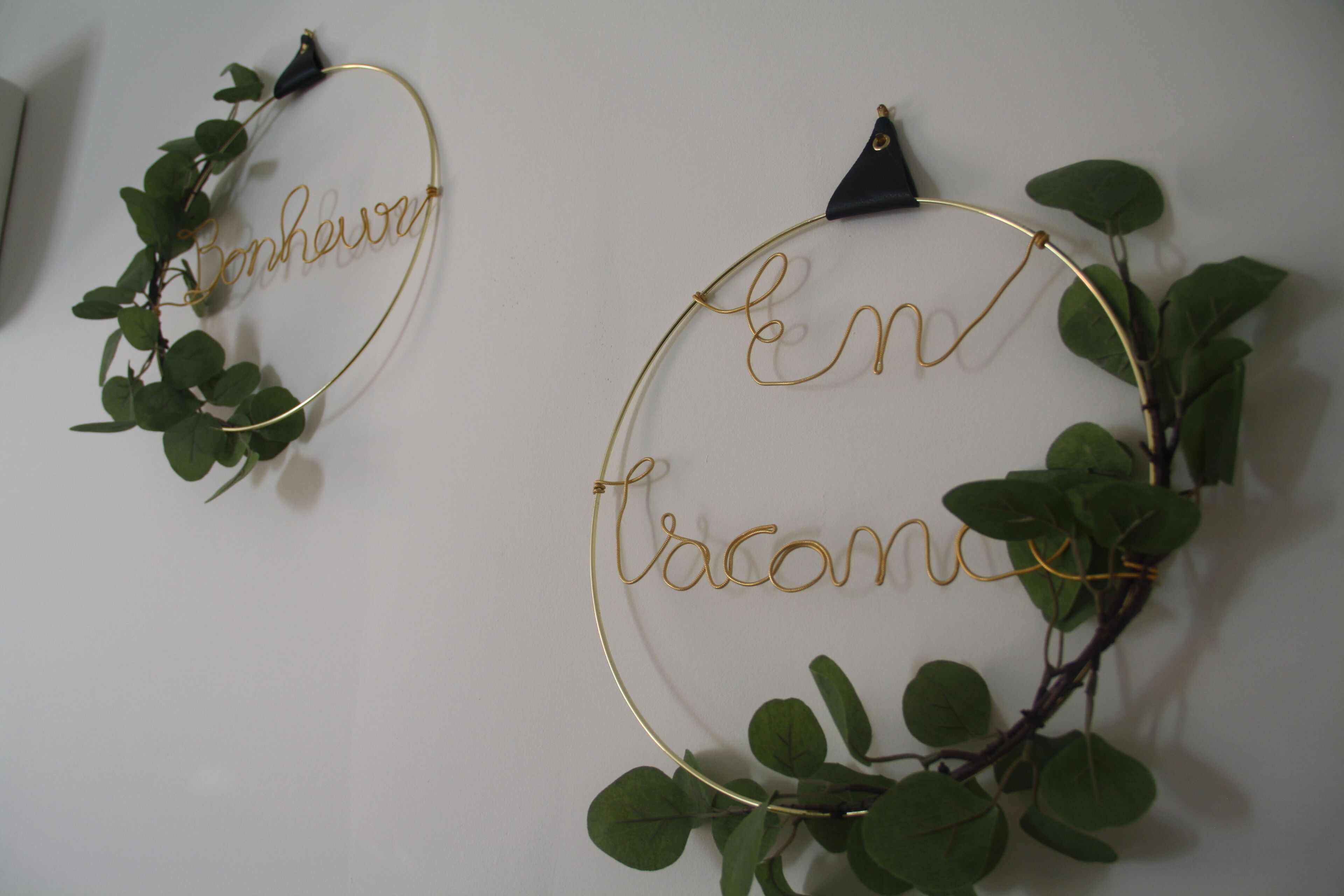 Twee ronde decoraties aan de muur, met tekst en planten.