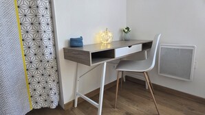 Een functionele werkplek met een houten bureau, een witte stoel en een wandradiator.