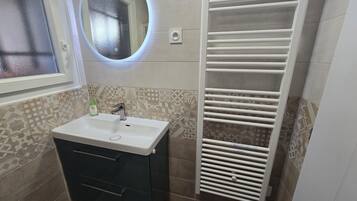 A bathroom with a sink, mirror, and towel rack.
